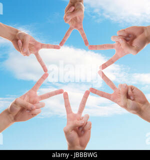 Une étoile faite de doigts de différentes personnes avec le ciel en arrière-plan Banque D'Images