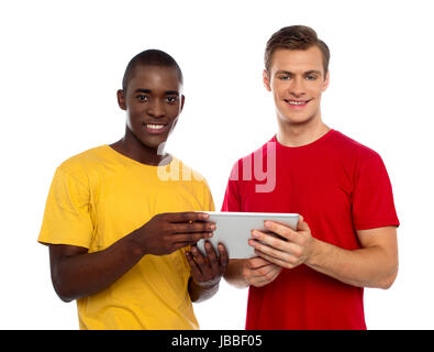 Des amis à l'aide de la technologie savvy tablet pc and smiling at camera Banque D'Images