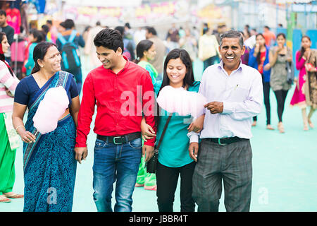 Heureux parents indiens avec son fils et sa fille marcher sur le partage juste et manger de la barbe à papa de suraj kund Banque D'Images