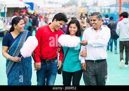 Heureux parents indiens avec son fils et sa fille marcher et manger de la barbe à papa de suraj kund market Banque D'Images