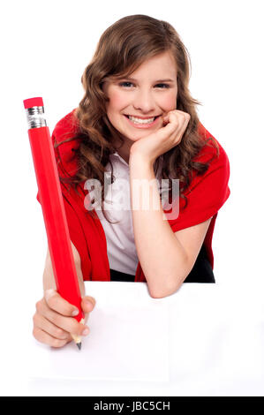 Heureux adolescent écrit avec l'aide de big red pencil and smiling at camera Banque D'Images