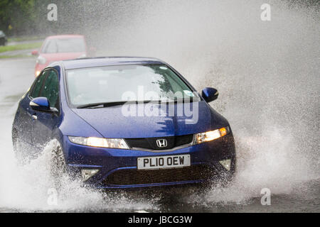 Les voitures qui circulent sur des routes inondées dans Tarleton, Lancashire, Royaume-Uni. Météo britannique. Inondation après des pluies torrentielles, ce qui rend difficile pour les conditions de conduite. Après une forte averse, la visibilité était extrêmement limitée, avec les flaques d'eau, l'eau de surface et un risque d'aquaplaning, avec une perte d'adhérence et réponse de la direction. Banque D'Images