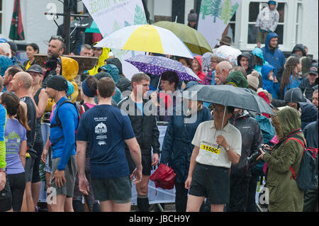 Llanwrtyd Wells, Royaume-Uni. 10 juin 2017. Spectateurs et porteur d'attendre sous la pluie pour thew départ de la course. Journée humide pour les concurrents dans l'homme V Horse Marathon. Porteur et chevaux en compétition dans les quelque 35 km homme cheval robuste sur marathon V terrain gallois. L'événement est parrainé par toute la terre et les aliments a été conçu en 1980 par Gordon Green après avoir entendu un débat à la pub Neuadd Arms, Llanwrtyd Wells, à savoir si l'homme était égale à l'exécution de cross country à distance. Credit : Graham M. Lawrence/Alamy Live News Banque D'Images