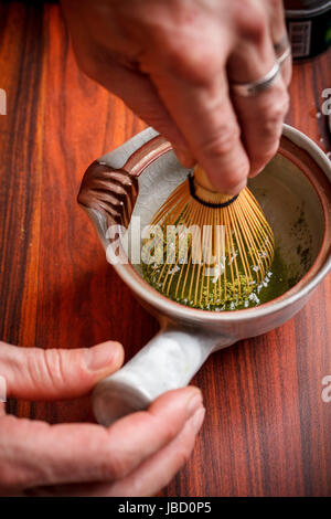En remuant au fouet avec du thé matcha Banque D'Images