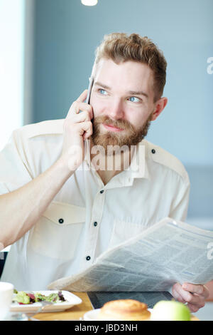 Homme d'appel avec journal à déjeuner dans cafe Banque D'Images