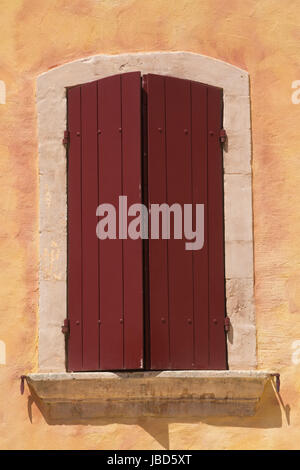 Vue rapprochée de l'ancienne fenêtre avec volets en bois rouge. L'architecture méditerranéenne. Provence, France. Banque D'Images