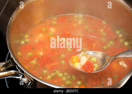 Soupe au poulet chaud d'être sortis de la poêle sur la cuisinière avec de la vapeur s'élevant de la soupe dans l'arrière-plan. Banque D'Images