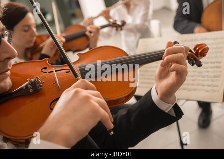 Violoniste confiant jouant son instrument et la lecture d'une feuille de musique classique, l'orchestre symphonique de la musique de fond sur la scène Banque D'Images