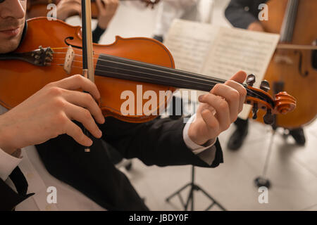 Violoniste confiant jouant son instrument et la lecture d'une feuille de musique classique, l'orchestre symphonique de la musique de fond sur la scène Banque D'Images