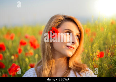 Portrait de femme blonde en robe blanche debout sur champ de coquelicots Banque D'Images