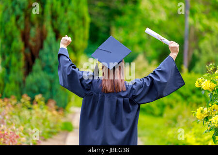 Jeune femme diplômée mettre ses mains et célébrer avec certificat dans ses mains et se sentant si le bonheur dans. Banque D'Images