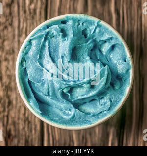 Cool bleu turquoise rafraîchissante glace dans un bain à remous à emporter debout sur une vieille table en bois texturé, vue de dessus en format carré Banque D'Images