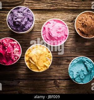 Crémeux savoureuses glaces italiennes colorés dans des bains à remous pour une fête ou occasion festive servi sur une vieille table en bois rustique, overhead view Banque D'Images