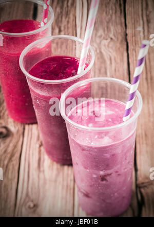 Trio de délicieux sains différents smoothies de fruits avec du yogourt faible en gras disposés dans une ligne diagonale, high angle view sur un vieux fond de bois rustique Banque D'Images