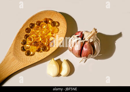 Perles de l'huile d'ail sur la cuillère en bois, l'huile d'ail gélules, comprimés de vitamines d Banque D'Images