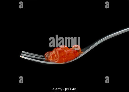 Caviar rouge dans la fourchette d'argent isolé sur un fond noir. Close up. Macro. Banque D'Images