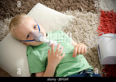 Boy making inhalation avec le nébulisateur à domicile. L'inhalation Inhalateur d'asthme de l'enfant malade à vapeur nébuliseur concept toux Banque D'Images