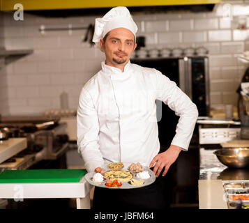 Jeune homme chef presenting dish Banque D'Images