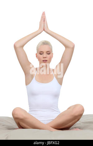 Woman meditating on a bed Banque D'Images