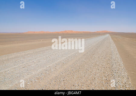 Route du désert rocailleux vide à l'Erg Chebbi dans le Sahara marocain, l'Afrique. Banque D'Images