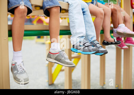 Les jambes de petits amis assis sur le swing ou d'autres installations récréatives Banque D'Images