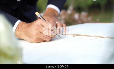 Le marié signe le registre des mariages après la cérémonie. Banque D'Images