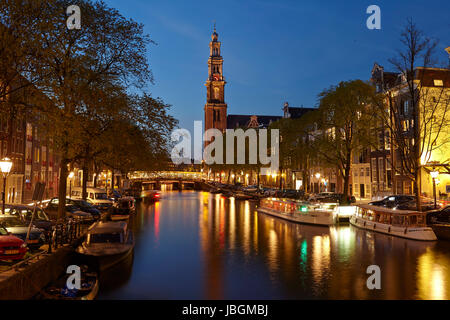 La photo est prise dans l'heure bleue et montre un canal et l'église Westerkerk (ouest) à Amsterdam. Les lumières de quelques lanternes sont refeflected dans l'eau. Banque D'Images