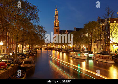 La photo est prise dans l'heure bleue et montre un canal et l'église Westerkerk (ouest) à Amsterdam. Les lumières de quelques lanternes sont refeflected dans l'eau. Banque D'Images