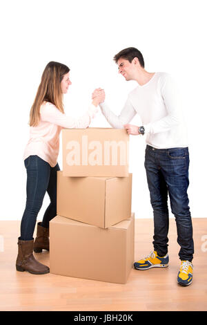 Jeune couple Arm wrestling boîtes de déménagement en nouvelle maison vacances Banque D'Images