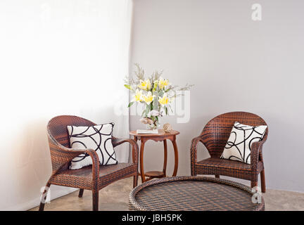 Table et chaises en rotin marron et fleurs Banque D'Images