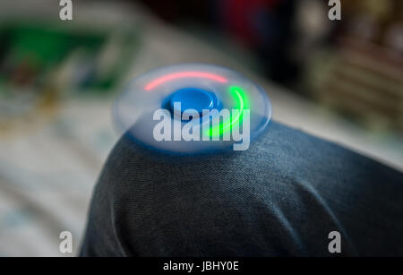 Hanovre, Allemagne. Le 08 juin, 2017. Un garçon a une filature Fidget Spinner sur son genou à Hanovre, Allemagne, 08 juin 2017. En raison de la longue durée d'exposition la LED ne s'allume que des bandes. Les disques avec un roulement à billes dans le centre travaillent tout à fait simple. Middlefinger et prise de pouce au centre et le trigger finger tourne. Photo : Silas Stein/dpa/Alamy Live News Banque D'Images