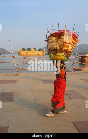 Femme indienne avec panier sur sa tête la marche par l'homme Sagar Lake à Jaipur, Rajasthan, Inde. Banque D'Images