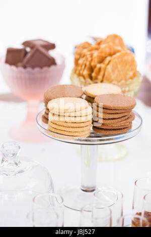 Libre de quatre piles de biscuit sec sur le verre au service de support avec morceaux de chocolat et les cookies dans des bols de gaufres en arrière-plan Banque D'Images