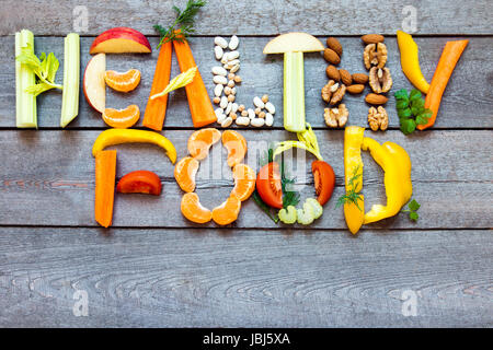 Mots 'Alimentation saine' écrit avec légumes, fruits, noix et légumineuses sur fond de bois rustique, concept - ingrédients biologiques pour vegan sain di Banque D'Images