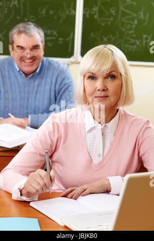 Portrait de blonde female looking at camera with senior man on background Banque D'Images