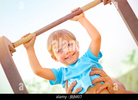 Closeup portrait of happy boy peu levée sur traverse, Daddy aider son fils à faire de l'exercice physique en plein air, heureux et en santé, concept de la petite enfance Banque D'Images