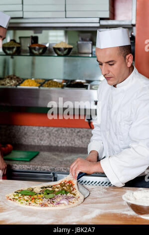 Chef d'essayer de sortir la pâte à pizza Banque D'Images