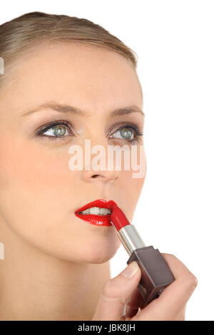 Woman putting on lipstick Banque D'Images