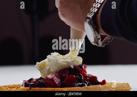 Une sélection de trois glaces italiennes la glace boules garnies de noix, chocolat, fruits servis sur les gaufres croustillantes Banque D'Images