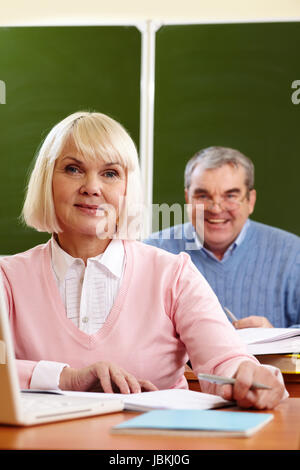 Portrait de blonde female looking at camera with senior man on background Banque D'Images