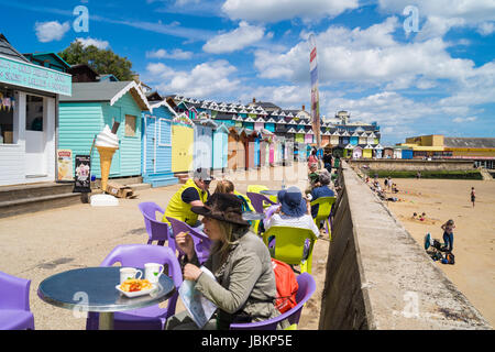 A woman eating chips et d'une famille jouissant de la crème glacée sur la promenade et de la plage des huttes, Walton sur l'Angleterre, Royaume-Uni,  ? Banque D'Images