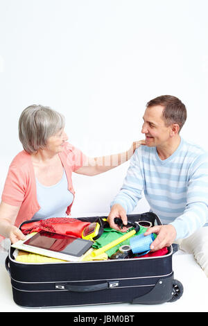 Portrait of happy senior couple packing suitcase Banque D'Images