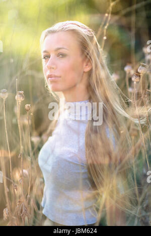 Portrait confiant belle blonde teenage girl in tall grass Banque D'Images