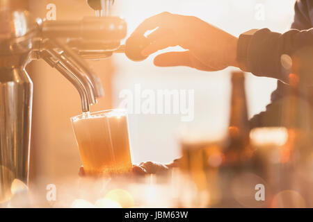 Close up homme bartender pouring pinte de bière de bière derrière bar Banque D'Images