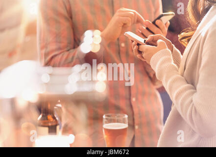 Homme et femme textos avec téléphone cellulaire et de boire une bière au bar Banque D'Images