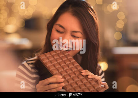 Femme avec la dent sucrée envie de mordre dans une grande barre de chocolat Banque D'Images