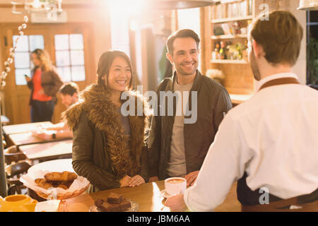 Servir le café barista pour couple at counter in cafe Banque D'Images