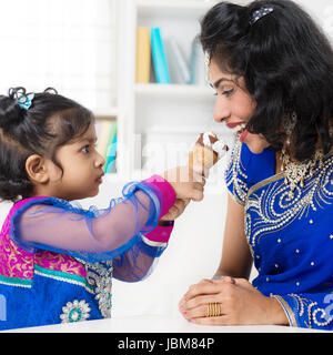 Indian girl nourrit sa mère des glaces. Mode de vie de la famille asiatique à la maison. Banque D'Images