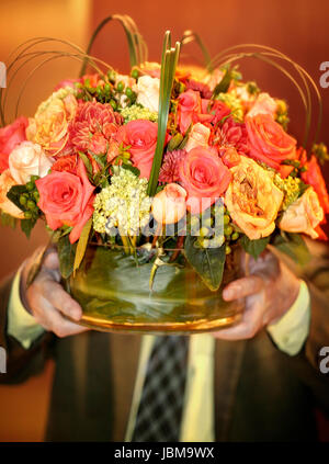 Homme portant vase avec fleurs. Visage masqué. Banque D'Images