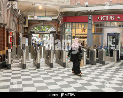 Une femme musulmane dans un hijab passe par l'achat de billets, les obstacles au Hammersmith et City Line Cercle underground station, London, UK Banque D'Images